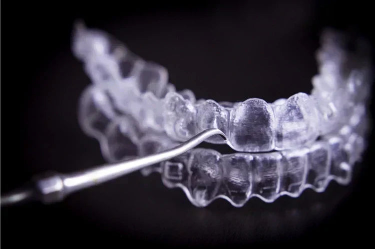 Een afbeelding van transparante aligners naast een instrument voor het reinigen van de mond