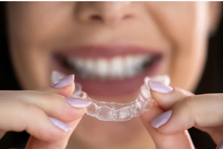 Een vrouw die nachtelijke transparante aligners aanbrengt