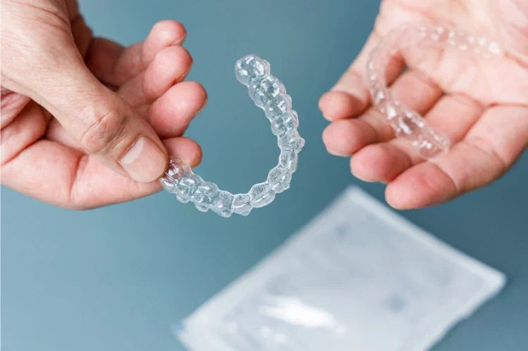 Handen die een paar transparante aligners vasthouden