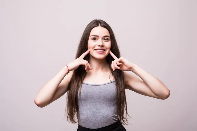 Een gelukkig meisje toont haar rechte glimlach