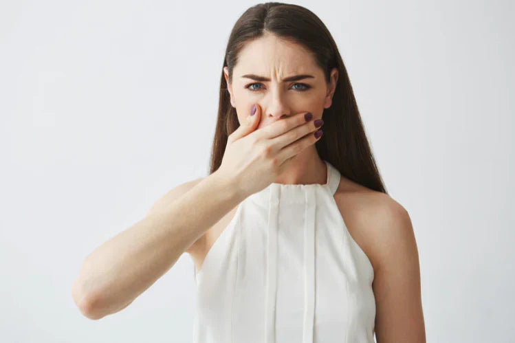 Een vrouw die uit schaamte haar hand voor haar mond houdt.