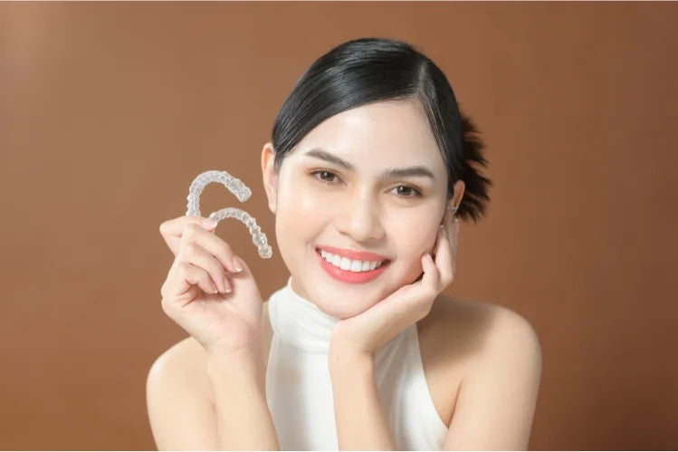 een mooie vrouw met symmetrische gelaatstrekken die transparante aligners vasthoudt